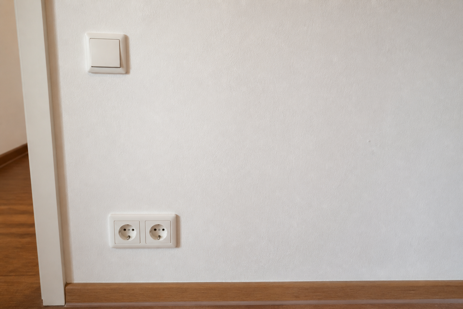 Steckdose und Lichtschalter an einer schlichten Wand